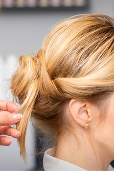 Close-up hairdresser styling blonde hair on the back of the head in a beauty salon