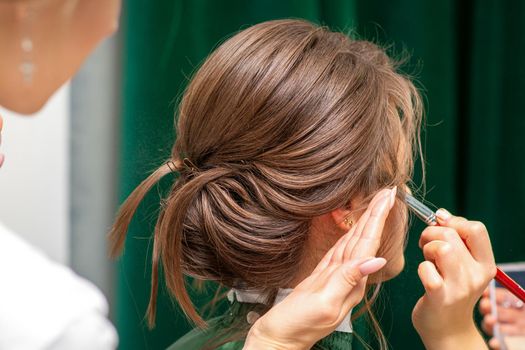 Stylist and makeup artist preparing bride before the wedding in a beauty salon