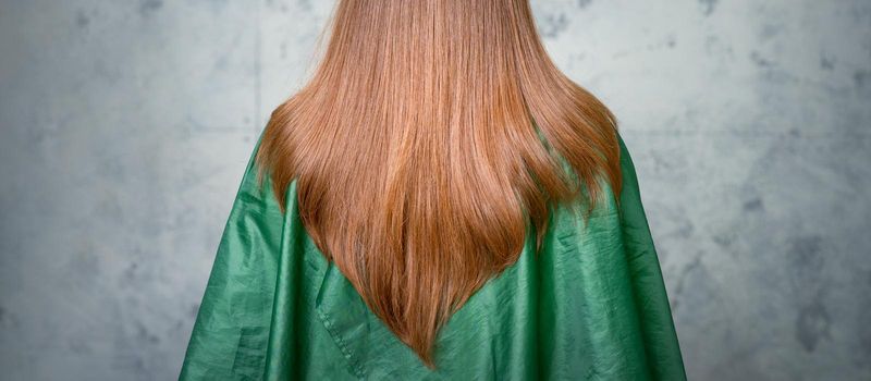Rear View of a woman with long brown hair against a gray background