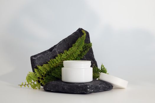 Unbranded natural cosmetic cream packaging standing on stone podium. Cream presentation on the white background. Mockup. Trending concept in natural materials. Natural cosmetic, skincare