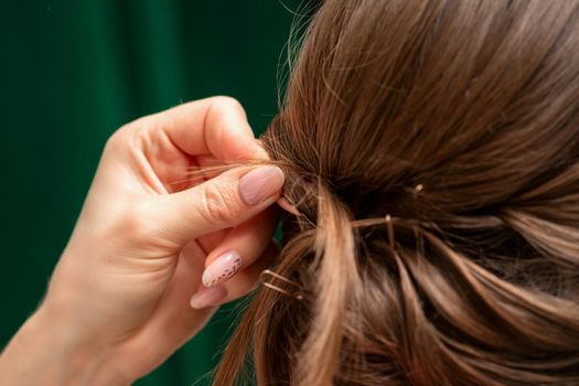 Hairdresser makes hairstyles for a young woman in beauty salon close up