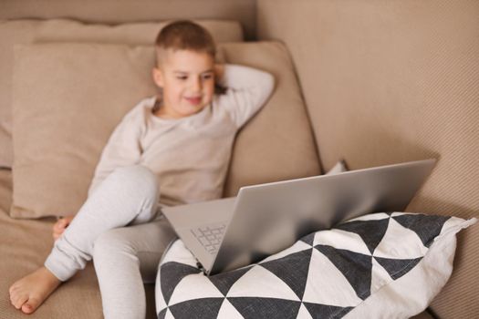 Child at home watching cartoon on the computer. Little boy and a laptop. Modern kid and education technology