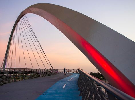 Teenager is riding his scooter on "Tolerance bridge" structure in Dubai. "Dubai water canal", UAE. Outdoors