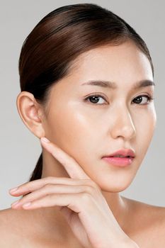 Closeup ardent young woman with healthy clear skin and soft makeup looking at camera and posing beauty gesture. Cosmetology skincare and beauty concept.