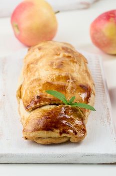 Baked strudel with apples on a white wooden board, delicious dessert