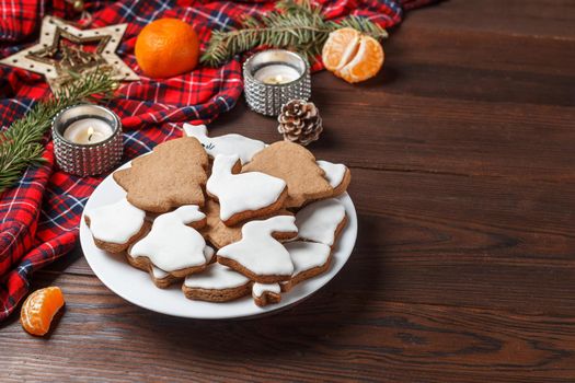 Delicious homemade Christmas cookies in the form of a rabbit and a Christmas tree on a wooden table decorated with New Year's decor. Copy spase