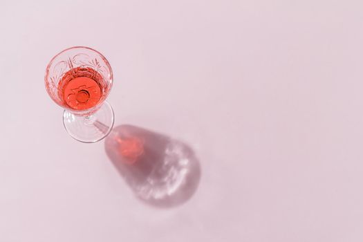 Minimalistic composition of a drink in a beautiful glass on a pink background. The concept of celebrating christmas and new year. copy space