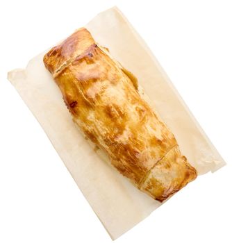 Whole baked strudel with fruit filling on parchment paper isolated on white background