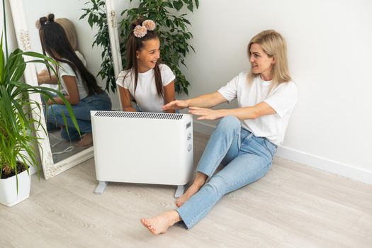 Cold home, freezing family, mother and daughter Sitting Near Heater.