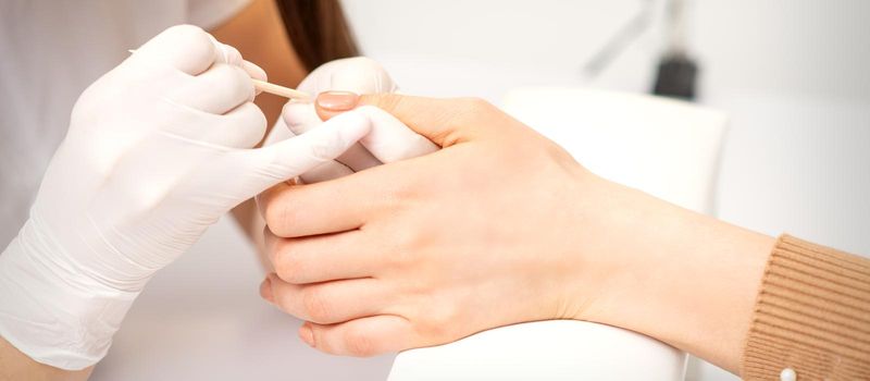 Young woman receiving pink or beige nail polish in a beauty salon