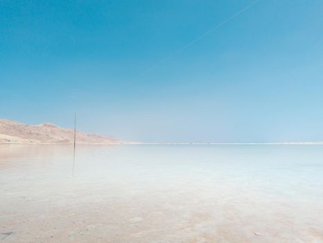 Landscape view on Dead Sea salt crystals formations, clear cyan green calm water at Ein Bokek beach, Israel