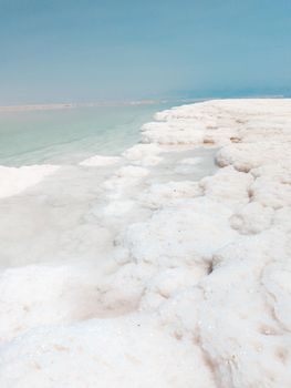 Landscape view on Dead Sea salt crystals formations, clear cyan green calm water at Ein Bokek beach, Israel