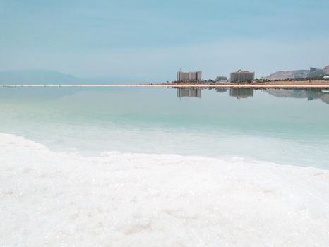 Landscape view on Dead Sea salt crystals formations, clear cyan green calm water at Ein Bokek beach, Israel