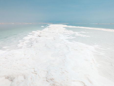 Landscape view on Dead Sea salt crystals formations, clear cyan green calm water at Ein Bokek beach, Israel