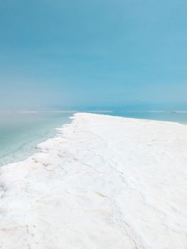 Landscape view on Dead Sea salt crystals formations, clear cyan green calm water at Ein Bokek beach, Israel