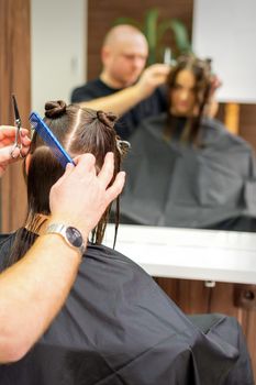 Male stylist cutting the hair of female client in professional beauty salon