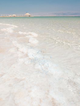 Landscape view on Dead Sea salt crystals formations, clear cyan green calm water at Ein Bokek beach, Israel