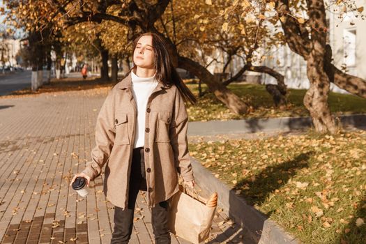 A stylish brunette woman walks around the autumn city. The season is autumn.