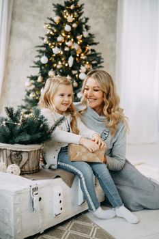 Happy family: mother and daughter. Family in a bright New Year's interior with a Christmas tree.