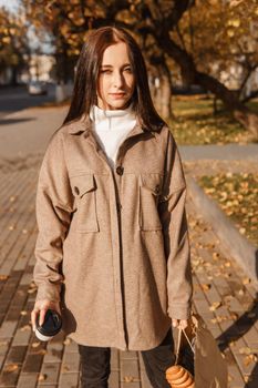 A stylish brunette woman walks around the autumn city. The season is autumn.
