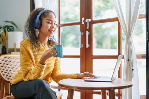 Portrait of an African American wearing headphones holding a coffee cup and using a computer.