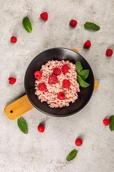 Healthy food on gray concrete background. Fresh raspberries risotto on a delicate and elegant dish