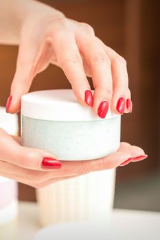 The woman opens the lid holding a jar of moisturizing cream, mockup, copy space, closeup