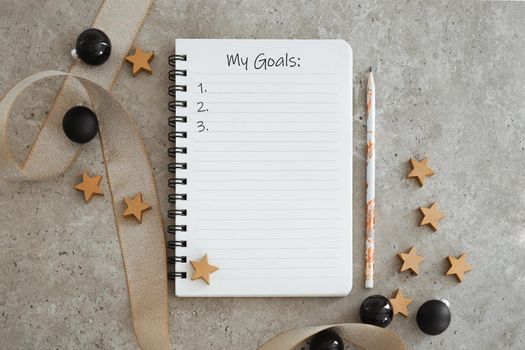Top view of notebook with Christmas decorations. Goals list for new year. Free space, copy space, mockup or template for your text
