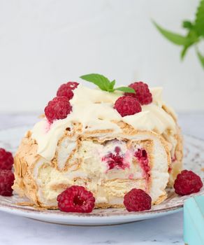 Baked meringue roll with cream and fresh red raspberry, white background	