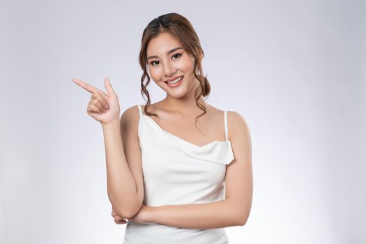 Photo of a gorgeous woman with flawless healthy fresh skin in a concept of empty space for beauty care product. Skincare product, model uses hand to create empty space for commercial.