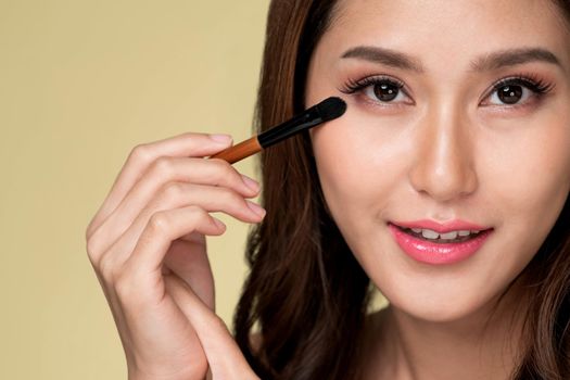 Closeup ardent young woman with healthy fair skin applying her eyeshadow with brush. Female model with fashion makeup. Beauty and makeup concept.