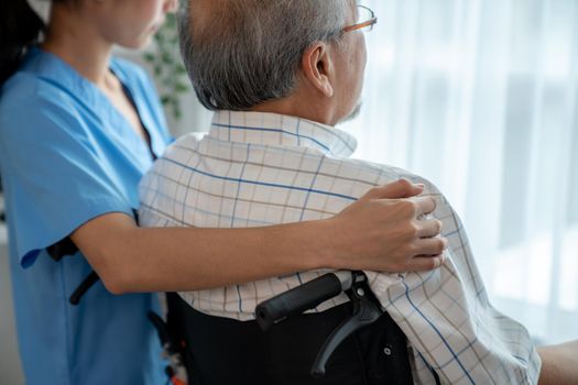 Rear view of a caregiver and her contented senior man gazing out through the window. Elderly health care, nursing homes for the elderly, and pensioner life