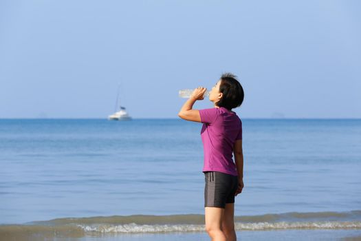 Fitness runner woman on ao nang beach , drinking water,Krabi , Thailand