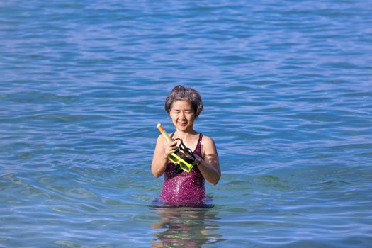 Senior asian woman with a mask for snorkeling in the sea.