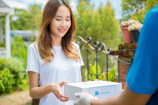 Asian woman sick she receive medication first aid pharmacy box hospital delivery service, Delivery man give medicine drug store to patient female at front home, healthcare medicine online business