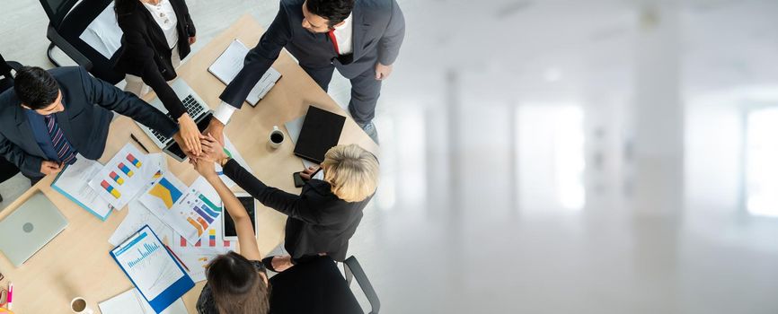 Happy business people celebrate teamwork success in widen view together with joy at office table shot from top view . Young businessman and businesswoman workers express cheerful victory .