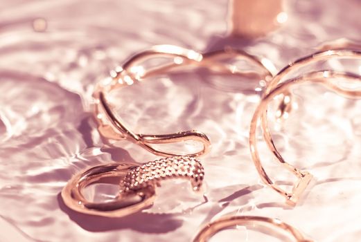 Jewellery branding, fashion gift and luxe shopping concept - Rose gold bracelets, earrings, rings, jewelery on pink water background, luxury glamour and holiday beauty design for jewelry brand ads