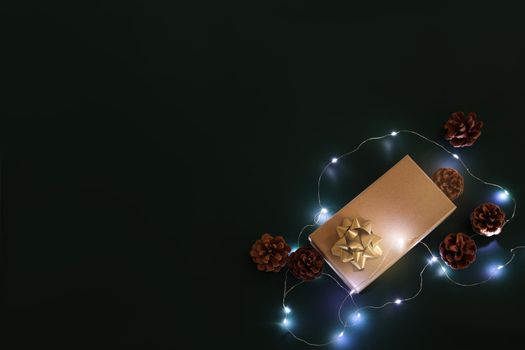 Christmas composition. Xmas background. Christmas gift and decoration elements on the dark background, fairy lights. Free space for text, copy space. Flat lay, top view.