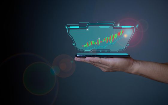 Hologram image of a candlestick chart from a phone on a person's hand. Offer trading, investment ideas