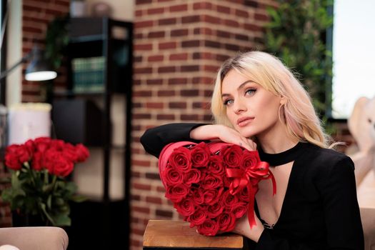 Beautiful thoughtful woman with roses romantic gift, valentines day date. Attractive blonde girlfriend with luxury presents posing, love holiday celebration, glowers delivery service