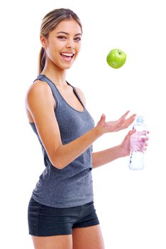 Healthy living - its not that difficult. Portrait of a sporty young woman holding a bottle of water and throwing an apple into the air