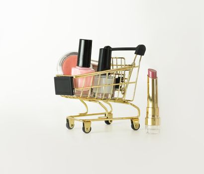 Shopping trolley full of make up and cosmetic goods on white background. Black friday concept. Sale and discount concept. Goods for women. Closeup of a basket with products for make-up.