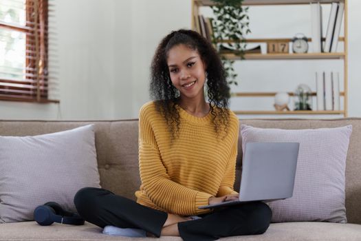 Attractive smiling young woman using laptop on sofa at home. lifestyle concept.