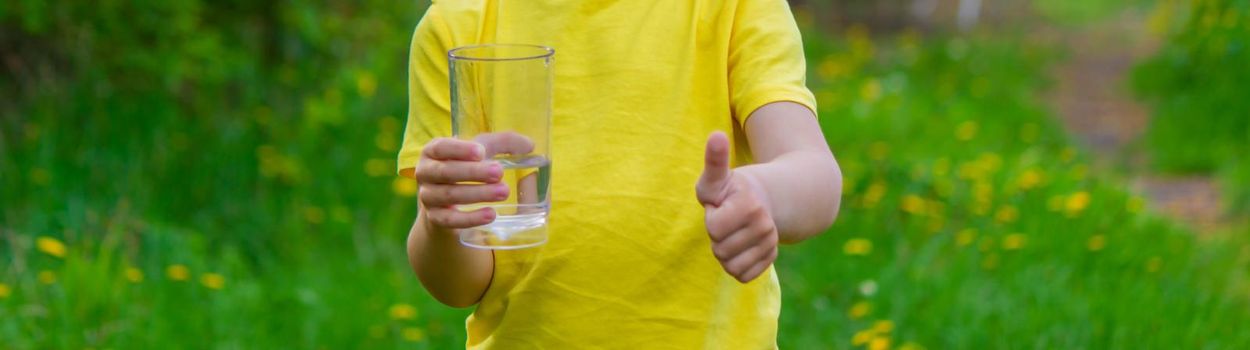 little boy drinking water with a glass in the park.Selective focus