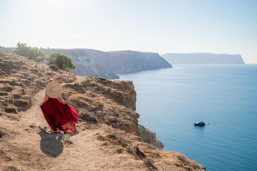 A woman in a red flying dress fluttering in the wind, against the backdrop of the sea