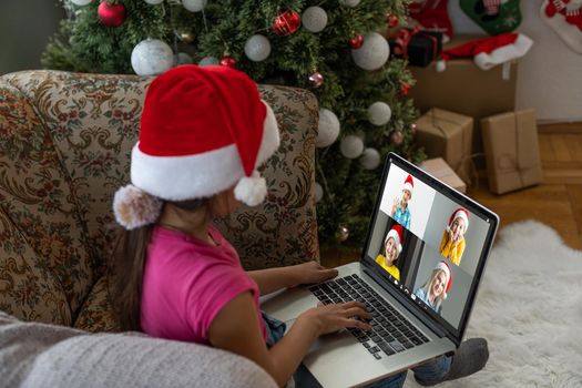 winter holidays, technology and children concept - little student girl with laptop computer at home over christmas tree background