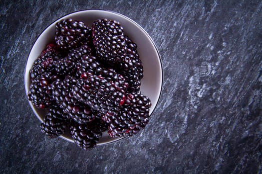 Blackberry berries. Black berries close-up on a wooden surface. Summer fruits are scattered on the table. Copyspace.