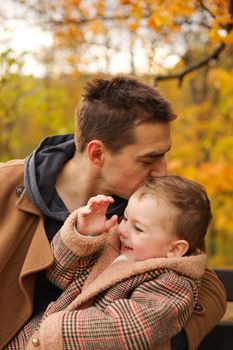 Father and son have fun together in park in autumn. Outdoor fun, autumn fallen leaves. Dad loves his boy