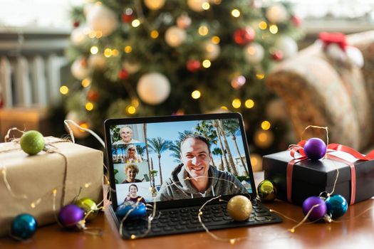 Young smiling man sitting on sofa at home and using digital tablet while relaxing in the cozy of his home