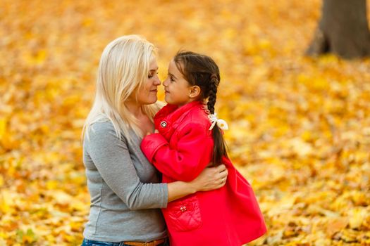 woman with daughter Outdoor having fun in autumn park.